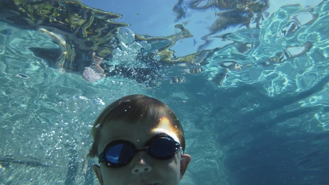 一名小男孩在水中跳入游泳池视频素材