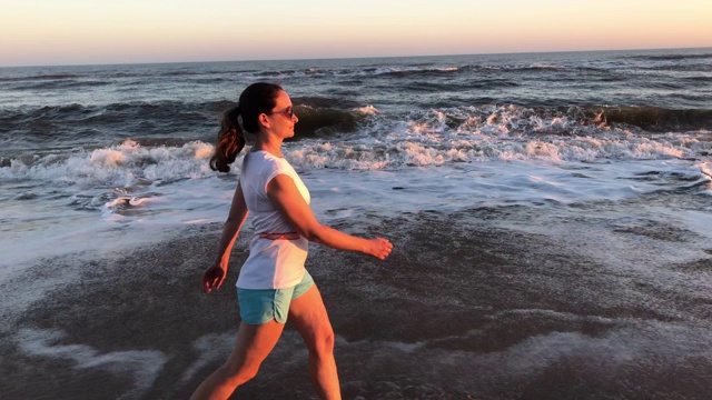 一个年轻女子在海滩上散步视频素材