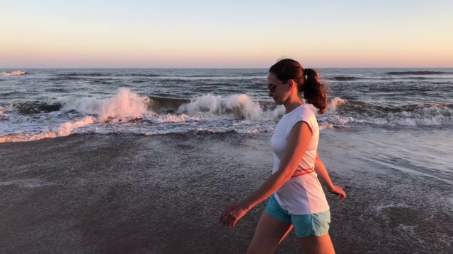 一个年轻女子在海滩上散步视频素材
