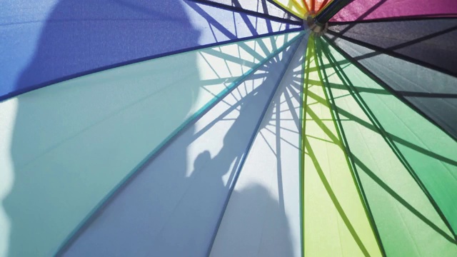 站在大街上的女人躲在五颜六色的伞后面。视频下载