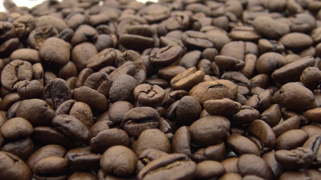 4k烘焙咖啡豆落在白色背景上。咖啡的原料视频素材