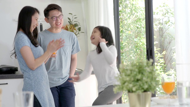 父母和女儿亚洲家庭跳和跳舞在房子的客厅。视频素材