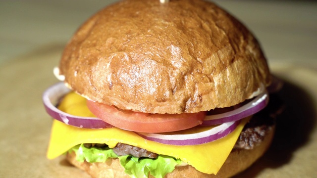 美味的汉堡配上牛肉片，生菜，番茄，洋葱，棕色的纸。视频素材
