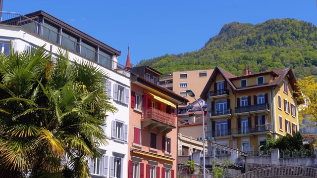美丽的多色瑞士房屋在一个小镇的街道上的山的背景视频素材