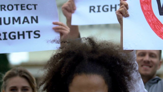 混血女孩举着“禁止种族主义”的牌子，激进分子挥舞着人权标语视频素材