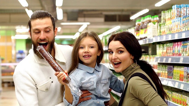 爸爸妈妈和女儿在店里买香肠，爸爸抱着女儿在怀里视频下载