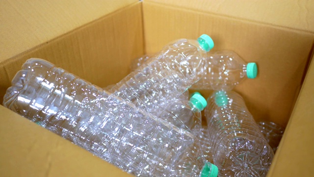 把水瓶扔进纸板箱。回收塑料瓶供回收。视频素材