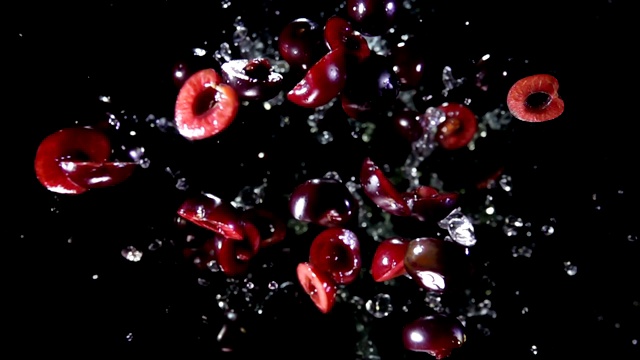 整颗和半颗带果汁的樱桃飞向了镜头视频素材