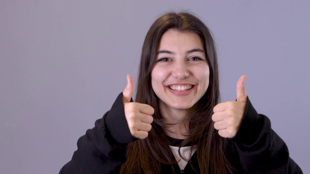 肖像拍摄的可爱的白人年轻女孩站在镜头前的蓝色墙壁背景和微笑愉快的4K视频视频素材