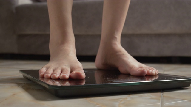 亚洲女性脚踩在数字体重秤上检查她的体重视频下载