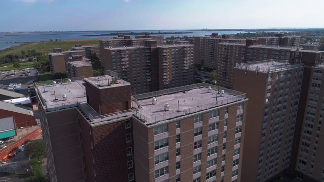 在纽约布鲁克林，沿着宾夕法尼亚大道，以Shirley Chisholm州立公园和牙买加湾为背景的多层社会“项目”砖砌建筑的住宅区。无人机视频与向前摄像机运动。视频下载