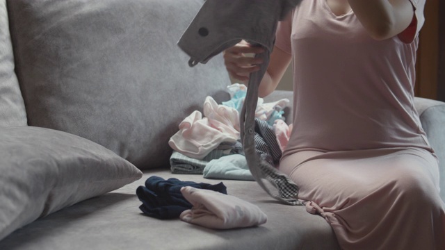 妈妈坐在沙发上叠婴儿的衣服视频素材