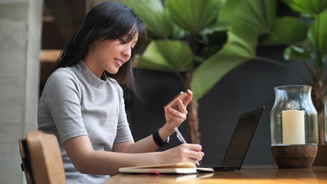 亚洲女性与智能手机在咖啡馆工作视频素材