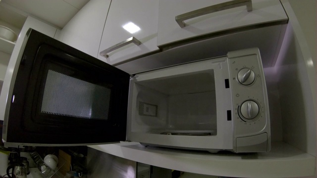 一个男人在厨房里使用微波炉的慢动作镜头视频下载