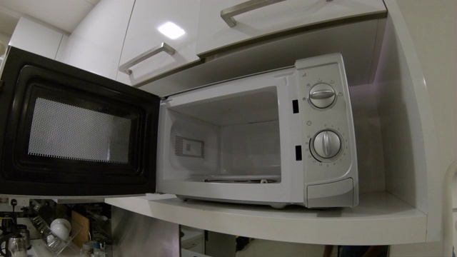 一个男人在厨房里使用微波炉的镜头视频下载