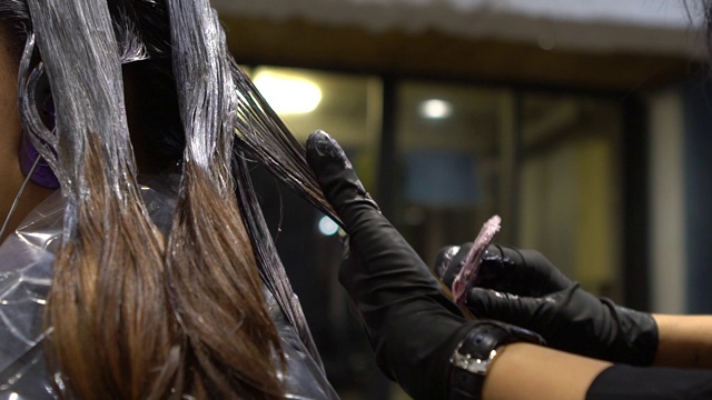 慢动作发型师使用染发剂提亮头发色调视频素材