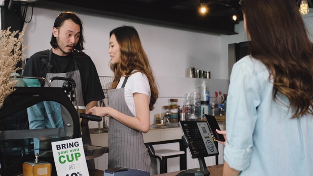 亚洲咖啡师错误地为使用手机支付的顾客点单视频素材