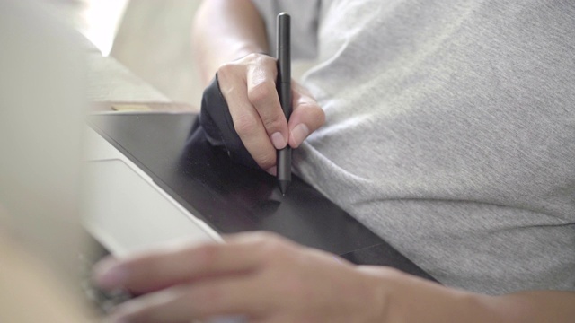 亚洲男性设计师工作在笔记本电脑与图形平板电脑和数字笔视频素材