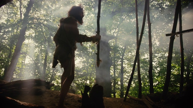 穿着兽皮和毛皮的原始穴居人手持石尖矛走出洞穴进入史前森林准备狩猎。尼安德特人进入丛林狩猎视频下载