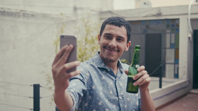 年轻的拉美男性拿着啤酒自拍(慢镜头)视频下载