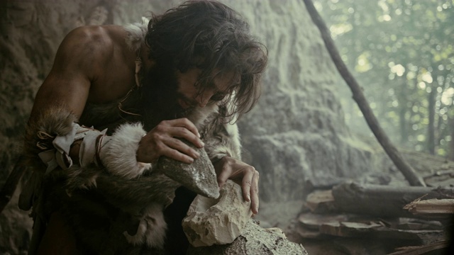 穿兽皮的原始穴居人用锋利的石头击打岩石，制造了第一个原始工具来狩猎动物的猎物。尼安德特人使用燧石。人类文明的黎明。慢动作特写镜头视频素材