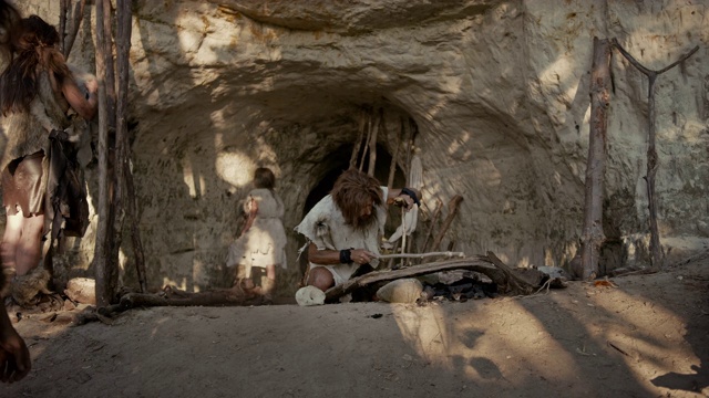 穿兽皮的原始穴居人用弓钻法生火。尼安德特人点燃人类文明史上第一次人造火。生火做饭。放大照片视频素材