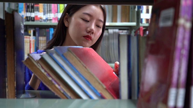 一个亚洲女人在图书馆找书的4k视频场景视频下载