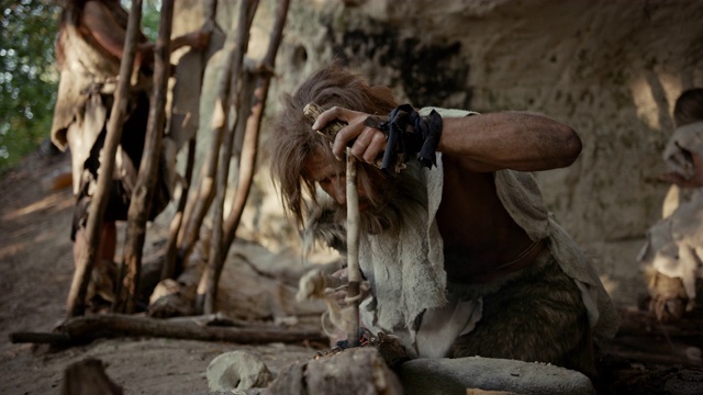 穿兽皮的原始穴居人用弓钻法生火。尼安德特人点燃人类文明史上第一次人造火。生火做饭。慢动作视频素材