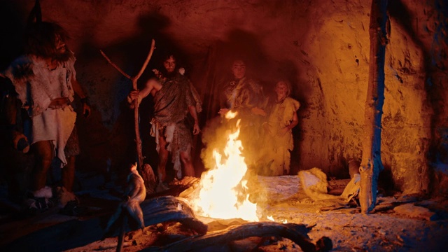 史前狩猎采集者部落穿着兽皮站在篝火外面的洞穴晚上。尼安德特人/智人家族在火旁进行异教仪式的肖像视频下载