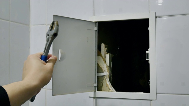 水管工人用扳手打开浴室管道小门视频下载