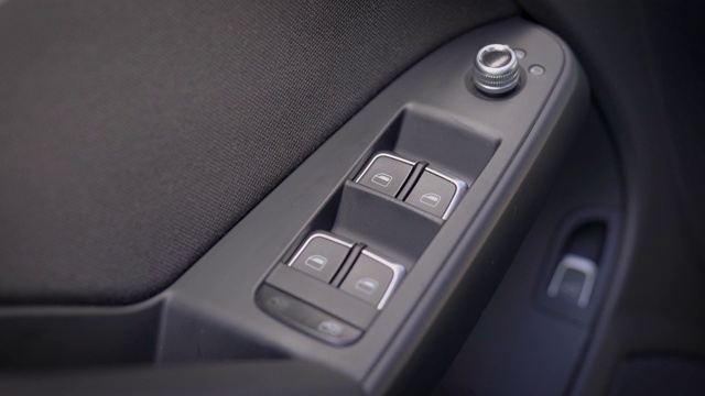 现代汽车内司机用遥控器按下车窗开关按钮，手的近景视频素材