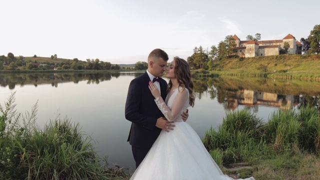 白种新郎和新娘在湖边的公园里。婚礼的夫妇。新婚夫妇视频下载