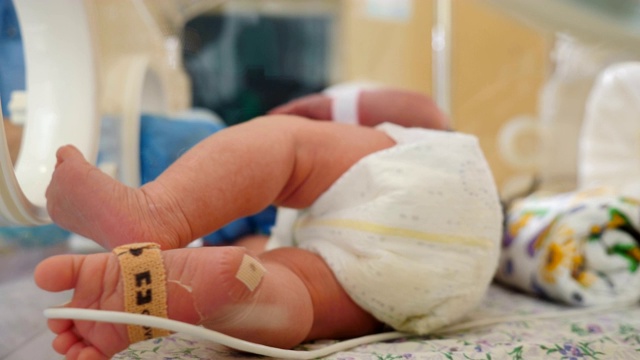 产科诊所。拯救生命的概念。在医生监护下的保育箱中的早产儿。特写婴儿婴儿的脚移动与医疗设备。4 k视频素材