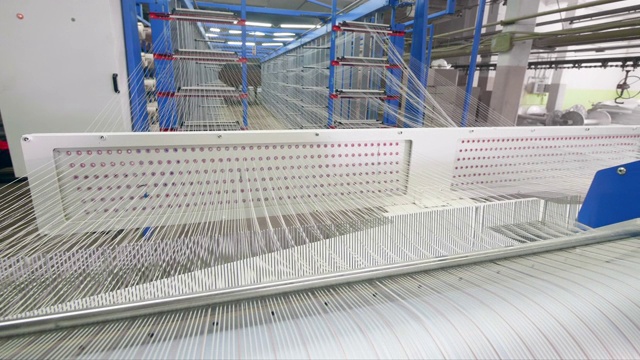 工厂的织机在设备室里织造白色纤维。视频下载