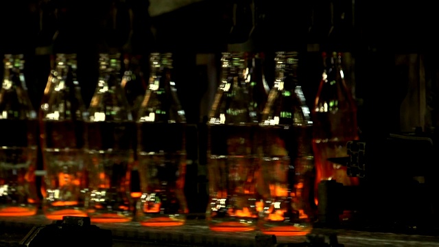 制造可乐瓶玻璃的工业工厂。在传送带上移动的透明空瓶。技术线生产视频下载
