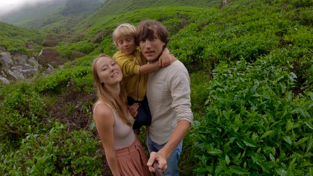 Slowmotion射杀。一对年轻夫妇和他们的儿子站在山上的一个大茶园里自拍视频下载
