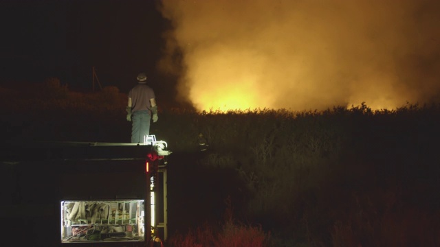 森林大火中，消防车在草地上燃烧。自然灾害的救助和预防视频素材