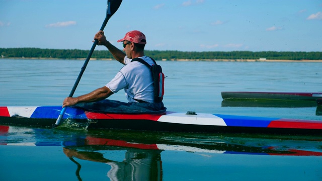 一个男人乘皮划艇横渡水面的侧视图视频下载