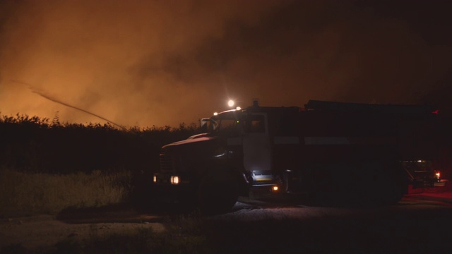 闪灯的消防车。森林大火中，消防车在草地上燃烧。自然灾害的救助和预防视频素材