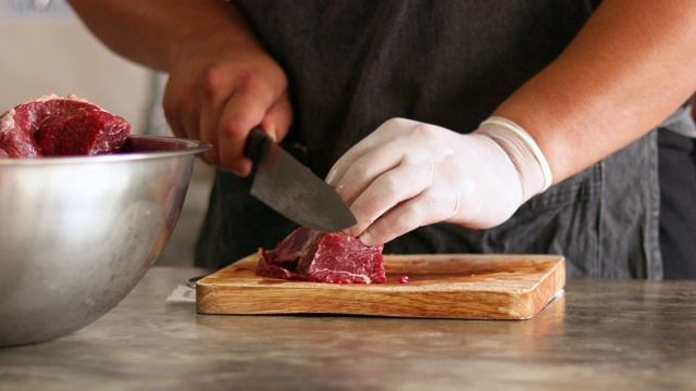 4K男人在木板上用刀手工切生牛肉，戴白手套，白天在家做饭视频素材