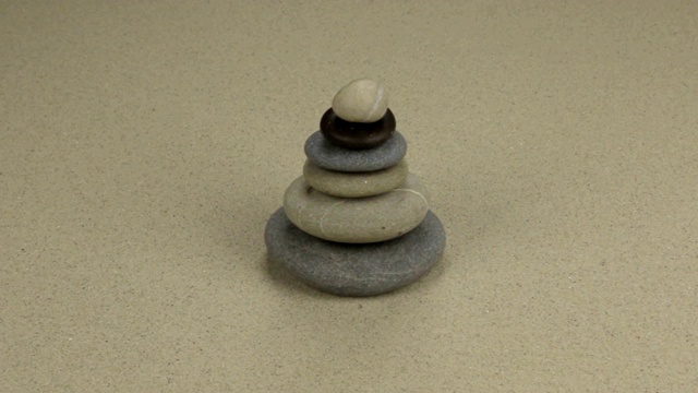 平衡的石头金字塔在沙滩上的沙子。滑块。视频素材