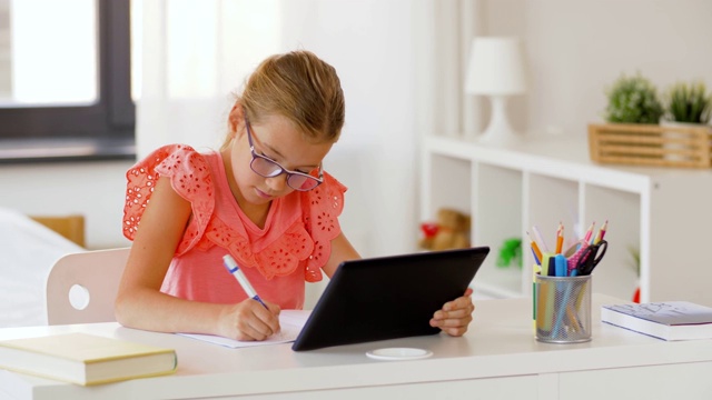 女孩用平板电脑在家里写笔记本视频素材