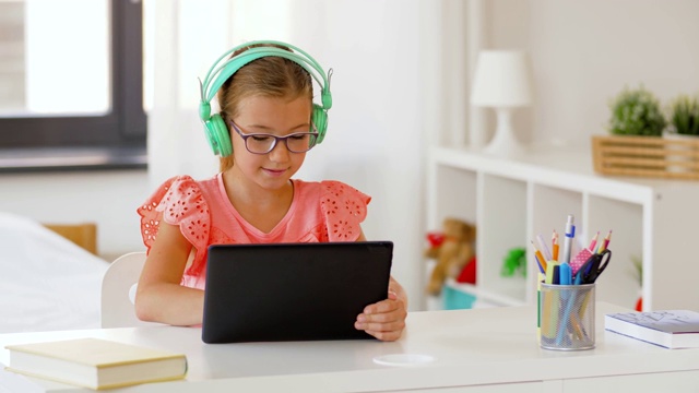 女孩戴着耳机，在家里用平板电脑视频素材