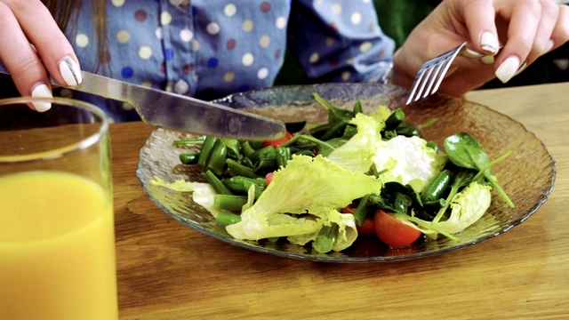 近距离拍摄的女性手拿着一叉新鲜的沙拉在餐厅。4 k视频素材