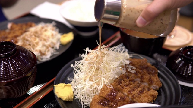 男子将沙拉酱和猪猪排(一种由面包屑组成的日本菜)倒在一起。视频下载