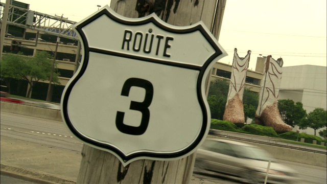 在德克萨斯州圣安东尼奥的3号公路上，车辆经过一尊牛仔靴雕像。视频下载