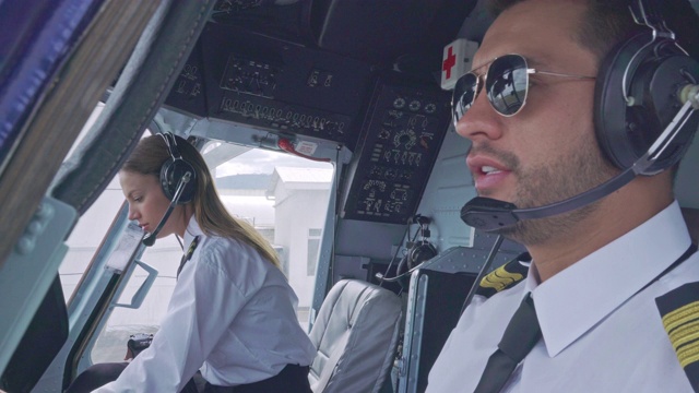 一名拉丁裔男性飞行员和一名白人女性飞行员在飞机起飞前在机舱内准备起飞。视频下载