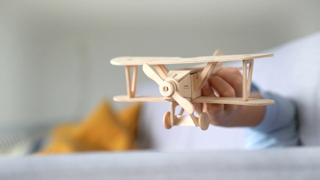 男孩的手玩木制飞机玩具模型的慢镜头。老式运输玩具概念视频。视频素材