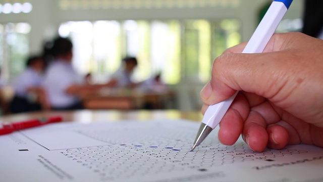 在学校或大学的考场上用铅笔将学生测试中的习题填写复写纸答题纸，在校园课堂上进行文件考试，教育或回到学校的概念视频下载