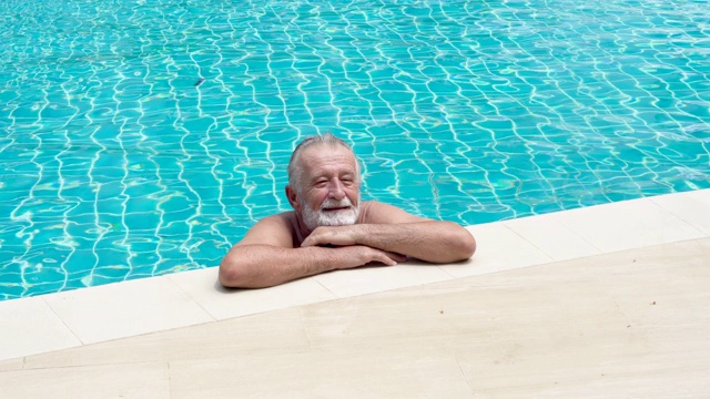 高级运动员站在游泳池里。老男人在泳池边休息。老年人锻炼。成熟的运动。视频下载